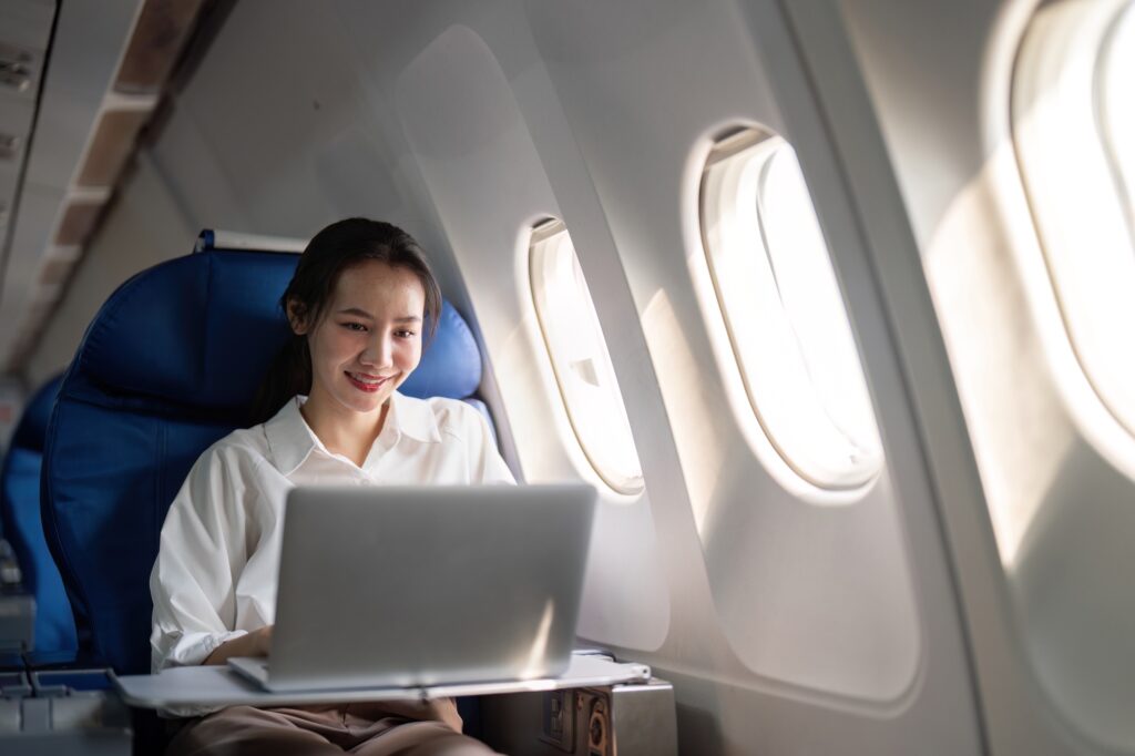 Successful young asian business woman sits in airplane cabin plane and working from anywhere